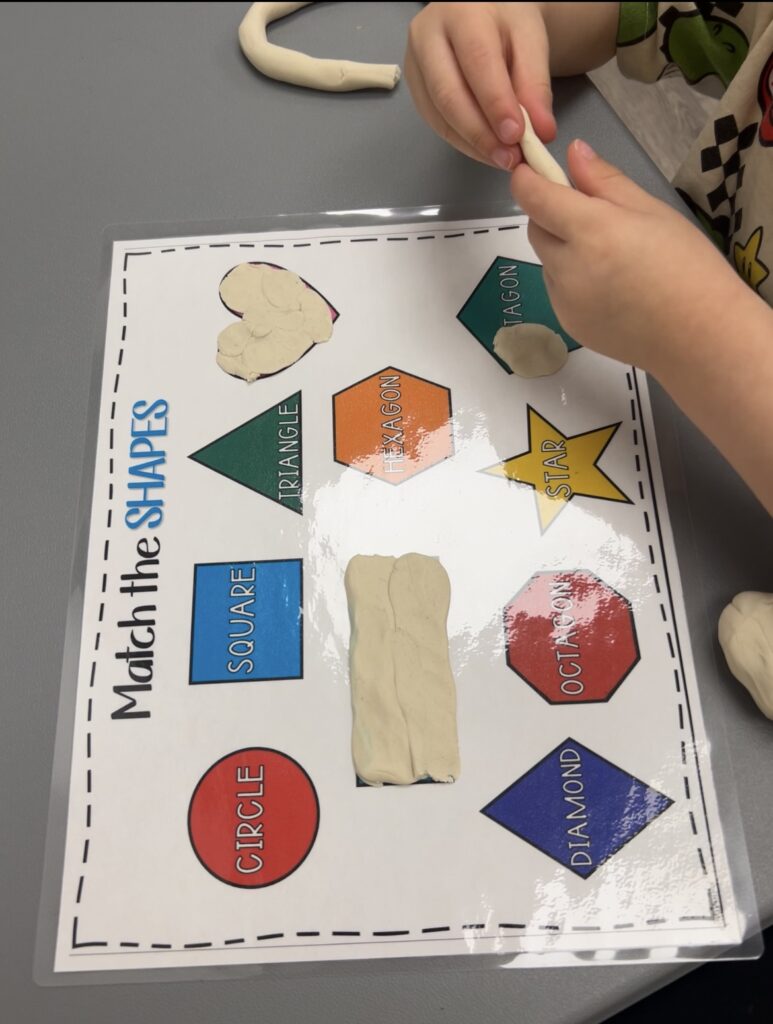 Child matching shapes with clay on a worksheet.