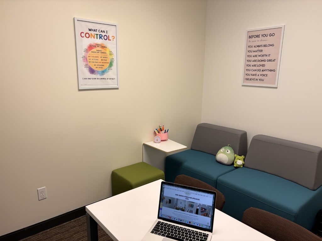 A cozy office corner with a sofa, laptop, and motivational posters on the walls.