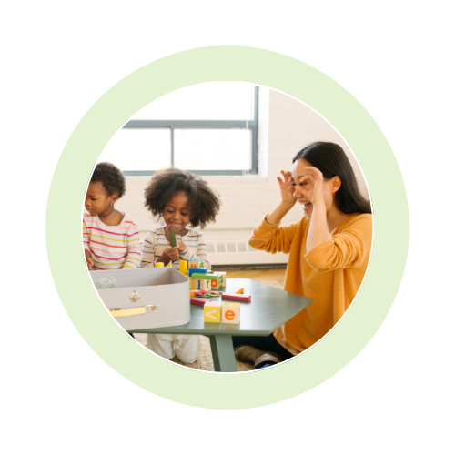 Teacher and children playing an educational game at a table.