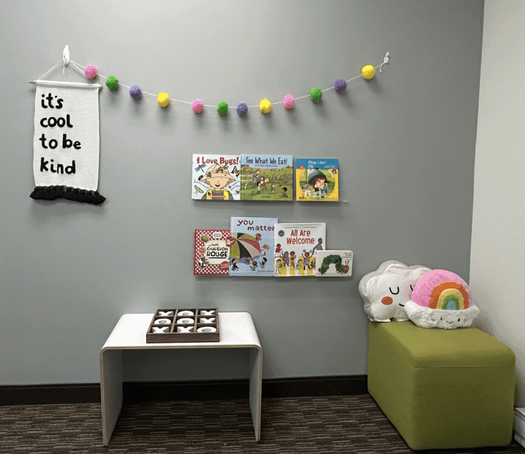 Cozy children's reading corner with colorful books, plush toys, and a small table with cupcakes.