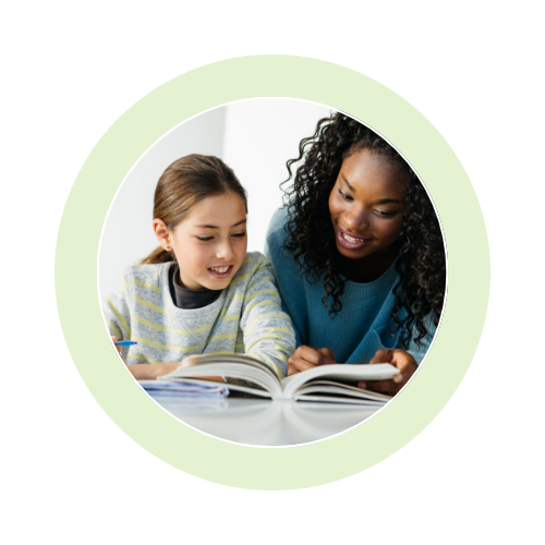 An adult and child reading a book together, smiling.